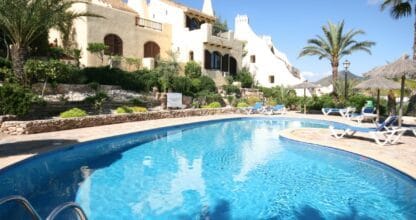Villa de estilo mediterráneo con piscina privada azul, hamacas y jardín de palmeras en alojamiento de La Manga Villas