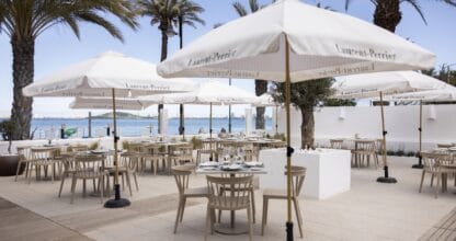 Terraza con sombrillas Laurent-Perrier, palmeras y vistas al Mar Menor en La Oliva Restaurante