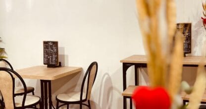 Interior de Cafetería La Pedregal desde 1977 con logo en pared blanca, mesas de madera y sillas negras