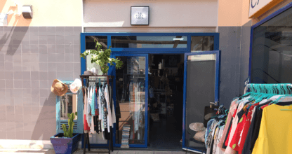 Pequeña boutique La Raya Azul con percheros de ropa en la acera y fachada de marco azul en La Manga del Mar Menor