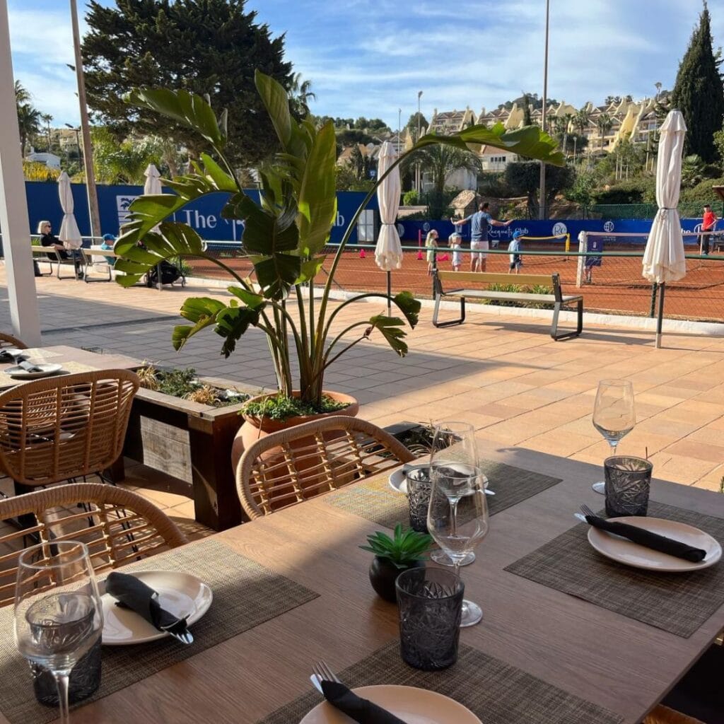 Terraza del restaurante La Terraza con mesas preparadas y vistas a las pistas de tenis de The Racquets Club