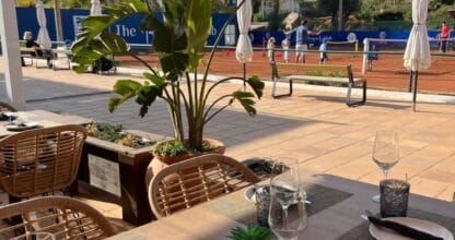 Terraza del restaurante La Terraza con mesas preparadas y vistas a las pistas de tenis de The Racquets Club