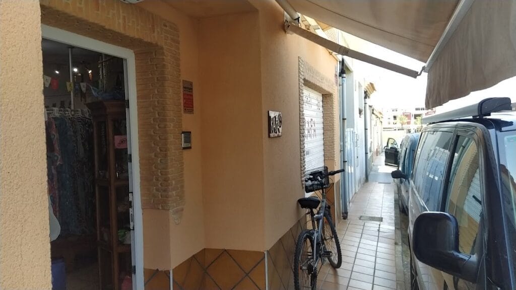 Fachada de La Tienda de Rafa en La Manga del Mar Menor, pequeño local de ropa con puerta abierta, toldo y bicicleta aparcada en la acera