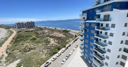 Vista aérea de edificio residencial con balcones azules frente al Mar Menor en La Manga, agencia Legal Spania MangaNorte