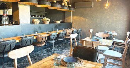 Sala interior de Leña & Karbon con mesas de madera, sillas de cuero y lámparas industriales, restaurante en La Manga del Mar Menor