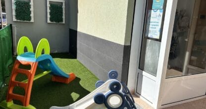 Zona exterior de Ludoteca Saltitos con toboganes infantiles de colores sobre césped artificial, La Manga del Mar Menor