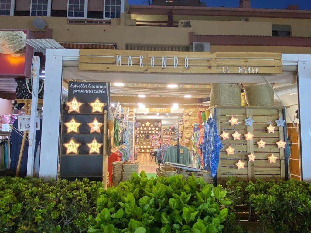 Fachada nocturna de Makondo La Manga, tienda de ropa y recuerdos decorada con estrellas luminosas y cajas de madera