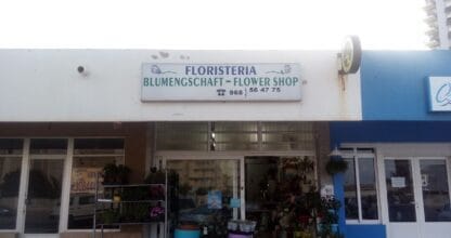 Fachada de la floristería Mara en La Manga del Mar Menor con plantas y flores en la entrada y cartel trilingüe español, alemán e inglés