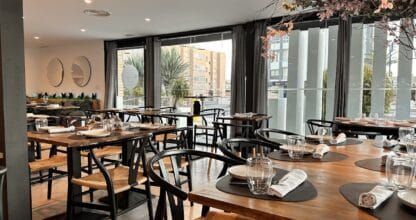 Interior del restaurante Marego's con mesas de madera, sillas negras y grandes ventanales con vistas a La Manga del Mar Menor