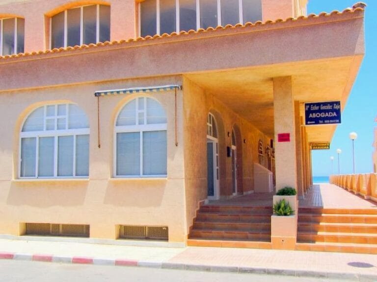 Fachada del despacho de la abogada María Esthér González Rája en La Manga del Mar Menor con acceso porticado junto al paseo marítimo