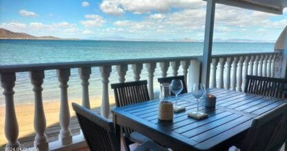 Terraza de Mariposa de Mar con mesa de madera y copas de vino frente a la playa y el Mar Menor en La Manga