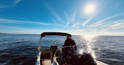 Persona al timón de lancha motora Marnific navegando en aguas abiertas bajo un cielo azul soleado