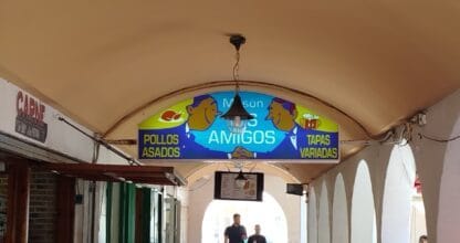 Portal con cartel de Mesón Los Amigos con pollos asados y tapas variadas, clientes sentados en galería de La Manga del Mar Menor