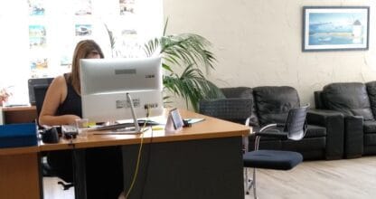 Oficina de MEDINASOL SERVICIOS en La Manga del Mar Menor con agente atendiendo en su escritorio y sofás de espera para clientes