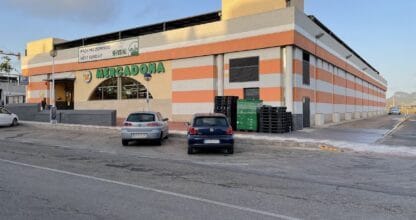 Exterior del supermercado Mercadona en La Manga del Mar Menor con fachada de franjas naranjas y dos coches aparcados frente a la entrada