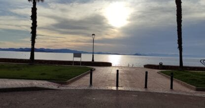 Paseo marítimo al atardecer con dos palmeras enmarcando la vista del Mar Menor desde el Mirador de La Manga