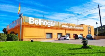 Edificio naranja de gran formato de Muebles Belhogar con rótulo Muebles-Furniture y bandera española en La Manga del Mar Menor