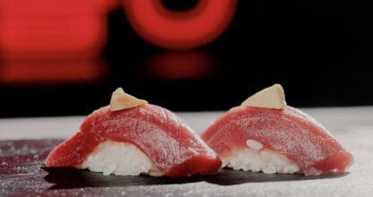 Dos piezas de nigiri de atún rojo sobre pizarra negra con luz roja de fondo en el restaurante Munashi Go