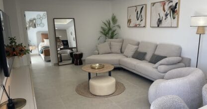 Salón moderno de propiedad gestionada por MyMoveEspaña con sofá gris, mesa de centro y cuadros decorativos
