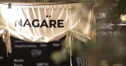 Entrada del restaurante Nagare con cartel de tela colgante, pizarra de menú y barra de madera rústica en primer plano