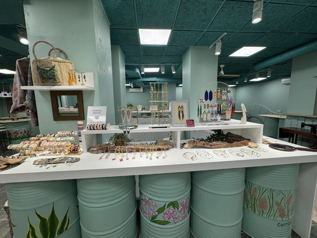 Interior de Nüa Shop Bisutería con mostrador decorado con barriles pintados y amplia exhibición de collares, pulseras y pendientes artesanales