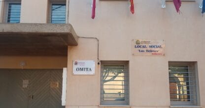 Fachada del Local Social Los Belones con cartel OMITA y banderas de la Región de Murcia