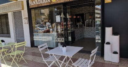Terraza exterior de Panadería Bernal Confitería en La Manga del Mar Menor con mesas y sillas blancas y escaparate de repostería