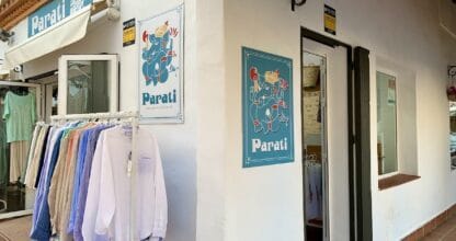 Fachada de Parati Plata La Manga con perchero de camisas de colores y carteles con logo de elefante azul en patio andaluz