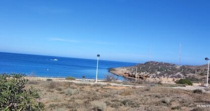 Vista panorámica de la costa rocosa de Cabo de Palos con mar azul intenso, barca y farolas desde el pareado vacacional