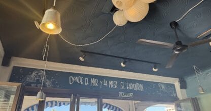 Interior de Patapalo tapas con techo oscuro, farolillos de papel y mural que reza donde el mar y la mesa se encuentran