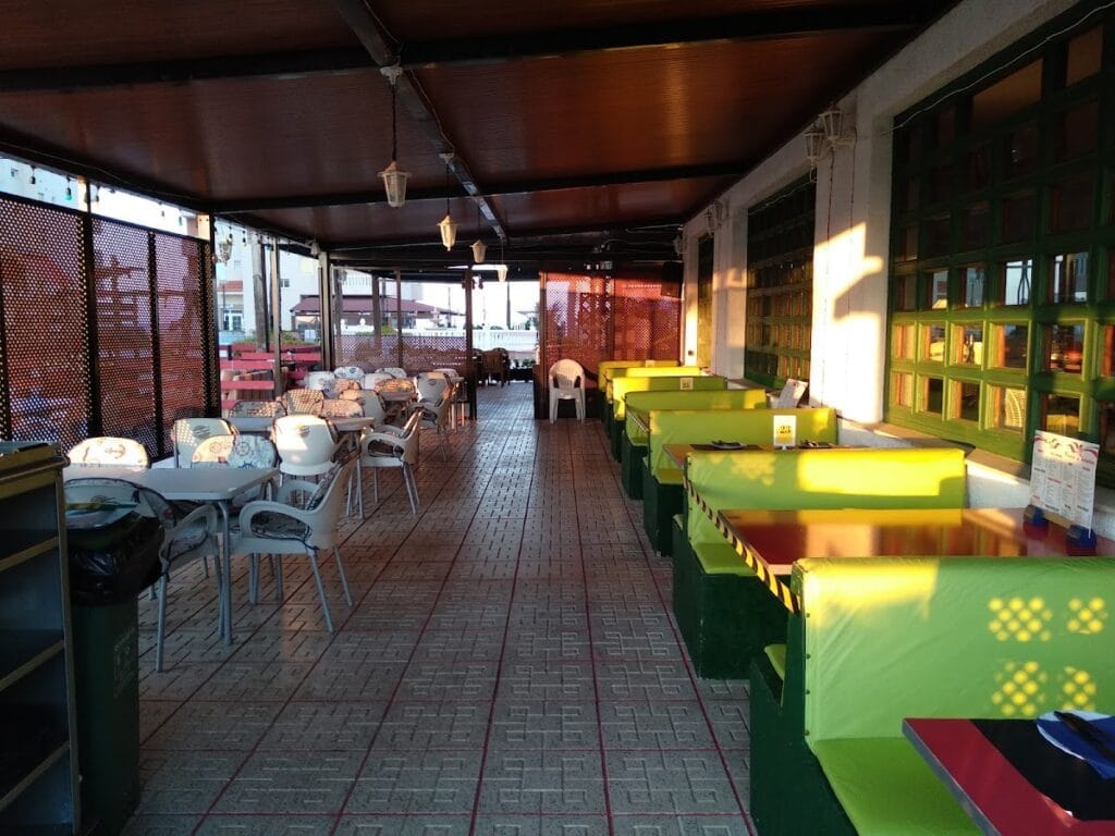Terraza cubierta de Pizzería Da Sebastián en La Manga del Mar Menor con booths verdes y sillas blancas de plástico