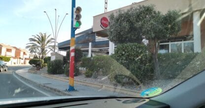 Vista exterior desde el coche de Pizzeria Las Dunas con semáforo en verde y palmeras en La Manga del Mar Menor