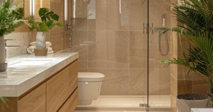Baño de lujo reformado con ducha de lluvia, mueble de madera y plantas tropicales, trabajo de Platinum Reformas