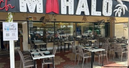 Exterior diurno del restaurante de ambiente surf Beach Mahalo en La Manga del Mar Menor, con terraza y gran rótulo con tabla de surf