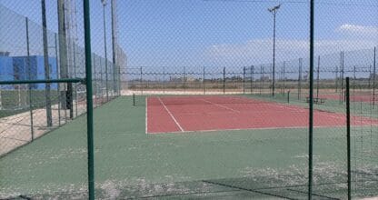Pista de tenis al aire libre con suelo rojo y verde en el Polideportivo Playa Paraíso, La Manga del Mar Menor