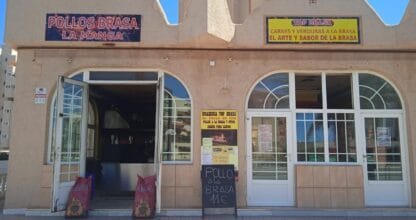 Fachada de Pollos Brasa La Manga con rótulos de brasería y cartel de pizarra anunciando pollo a la brasa para llevar