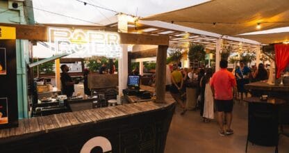 Puesto Proper Burger con cartel neón en la terraza del gastromercado La Fresca al atardecer, ambiente animado en La Manga