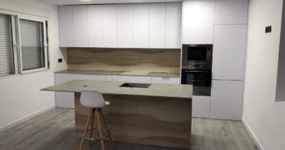 Cocina moderna renovada con isla central y armarios blancos, obra de TeodoReformaS en La Manga del Mar Menor