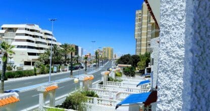 Terraza de apartamento residencial con vistas a la avenida principal de La Manga del Mar Menor, palmeras y edificios en verano