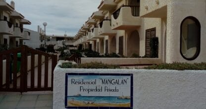 Entrada del Residencial Mangalán en La Manga del Mar Menor con cartel cerámico y adosados blancos de estilo mediterráneo
