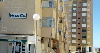 Fachada amarilla del Residencial Maracaibo en La Manga del Mar Menor con rótulo visible y local comercial en planta baja