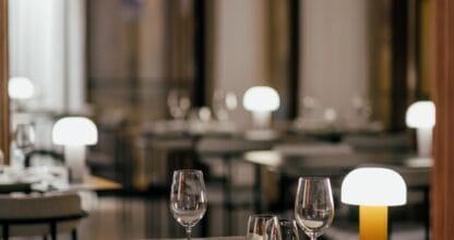 Sala interior elegante del Restaurante Amura con mesas negras preparadas, copas de vino y lámparas de ambiente cálido