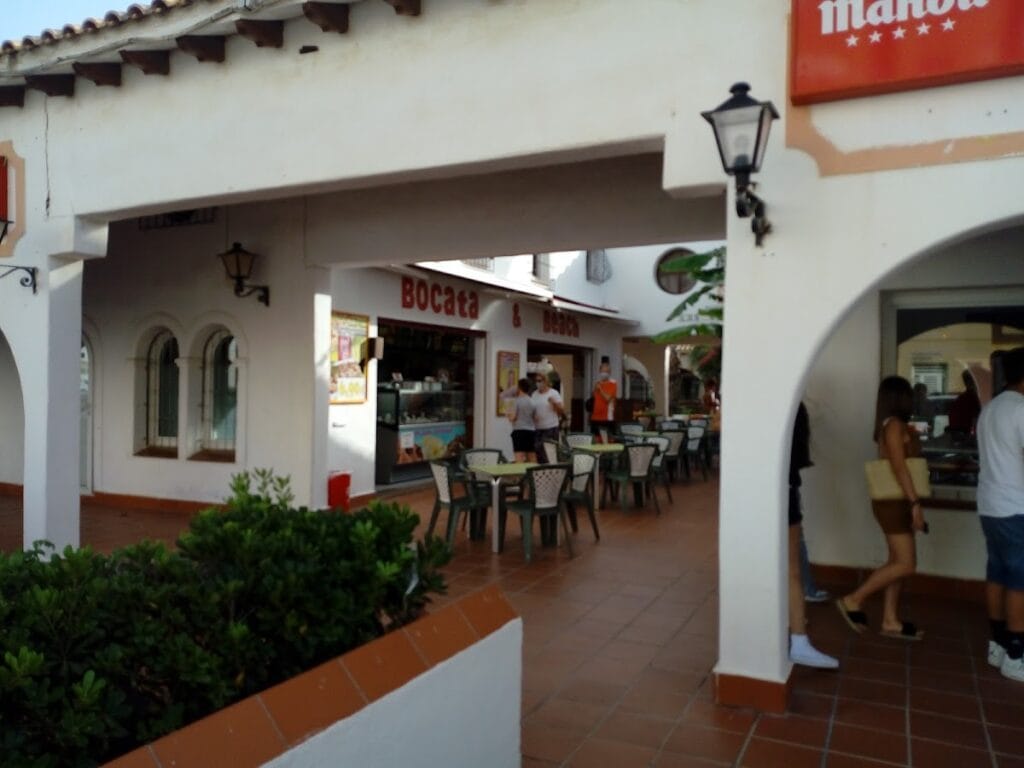 Fachada del restaurante Bocata and Beach en galería comercial blanca con mesas exteriores en La Manga del Mar Menor