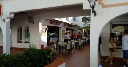 Fachada del restaurante Bocata and Beach en galería comercial blanca con mesas exteriores en La Manga del Mar Menor