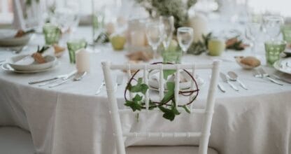 Mesa de banquetes del Restaurante del Hotel Entremares con mantel blanco, copas de cristal, velas y decoración de hojas verdes