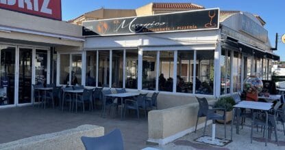 Terraza exterior del Restaurante El Mesónico Pizzería en La Manga del Mar Menor con mesas blancas bajo cielo azul