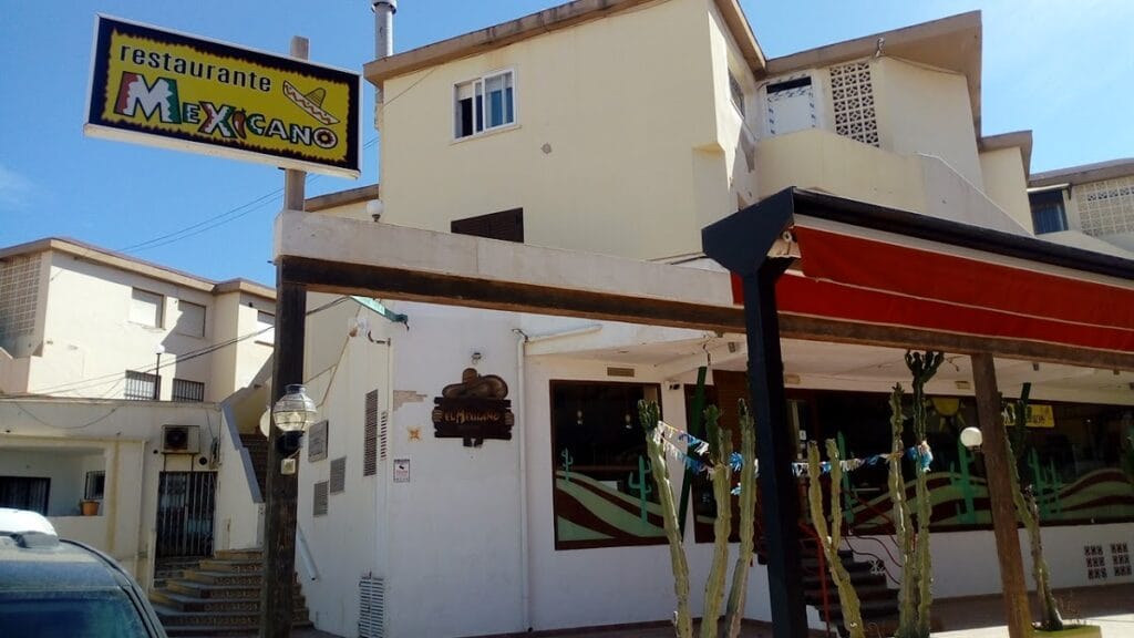 Fachada exterior del Restaurante El Mexicano en La Manga del Mar Menor, con cartel amarillo, toldo rojo y cactus decorativos