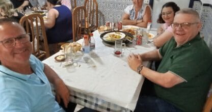 Comensales disfrutando de una comida en el Restaurante Isla Cristina con paredes de azulejos blancos y azules tradicionales