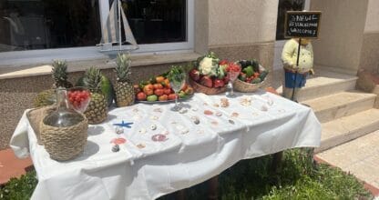 Mesa decorativa de bienvenida en Restaurante La Balandra con frutas frescas, verduras y conchas marinas al aire libre