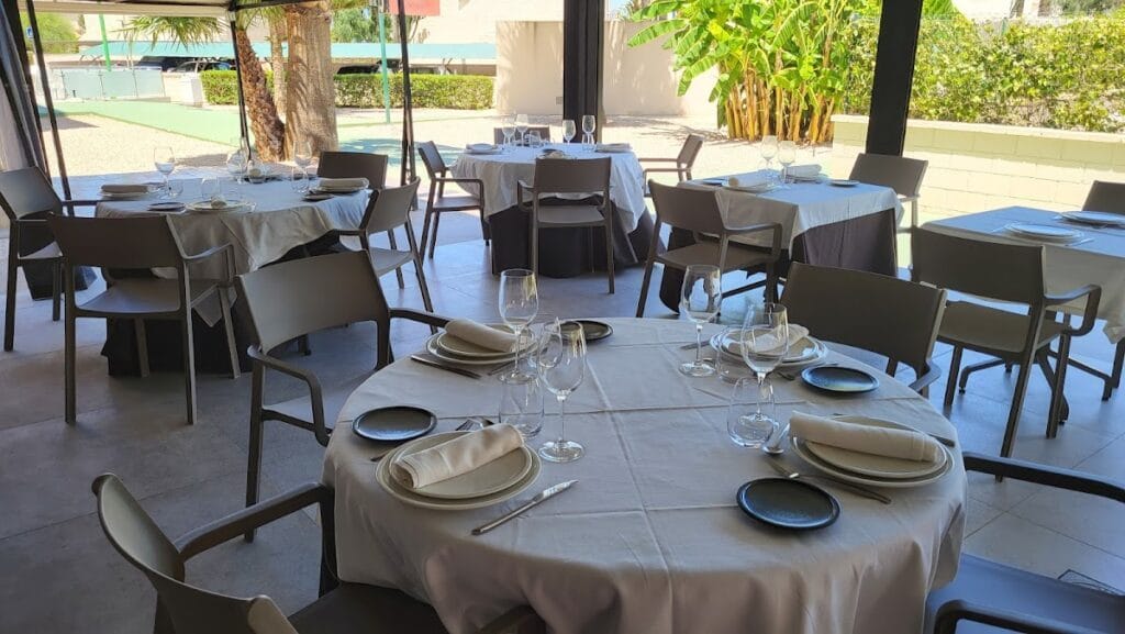 Terraza exterior con mesas redondas y vajilla elegante del Restaurante Malvasía en Playa Honda